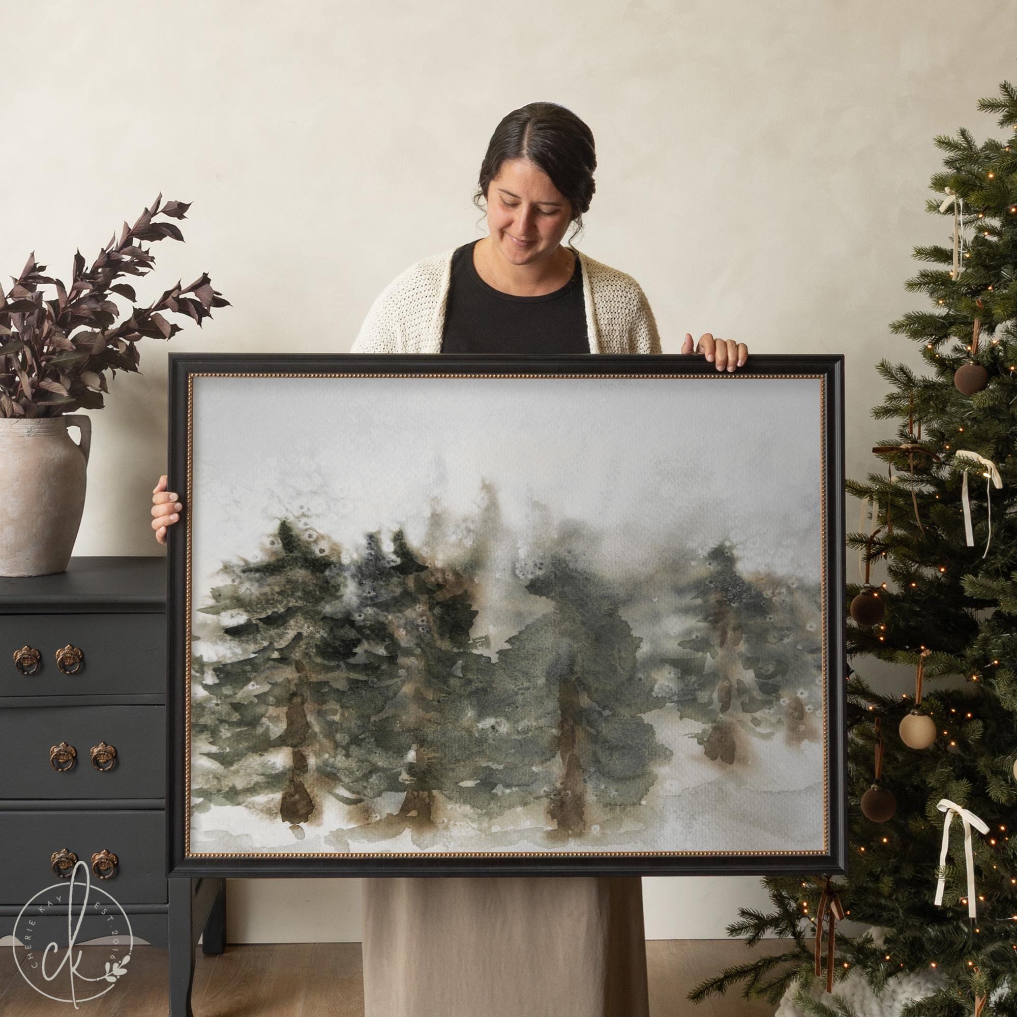 Framed Christmas wall art with watercolor pine trees in a winter forest scene.