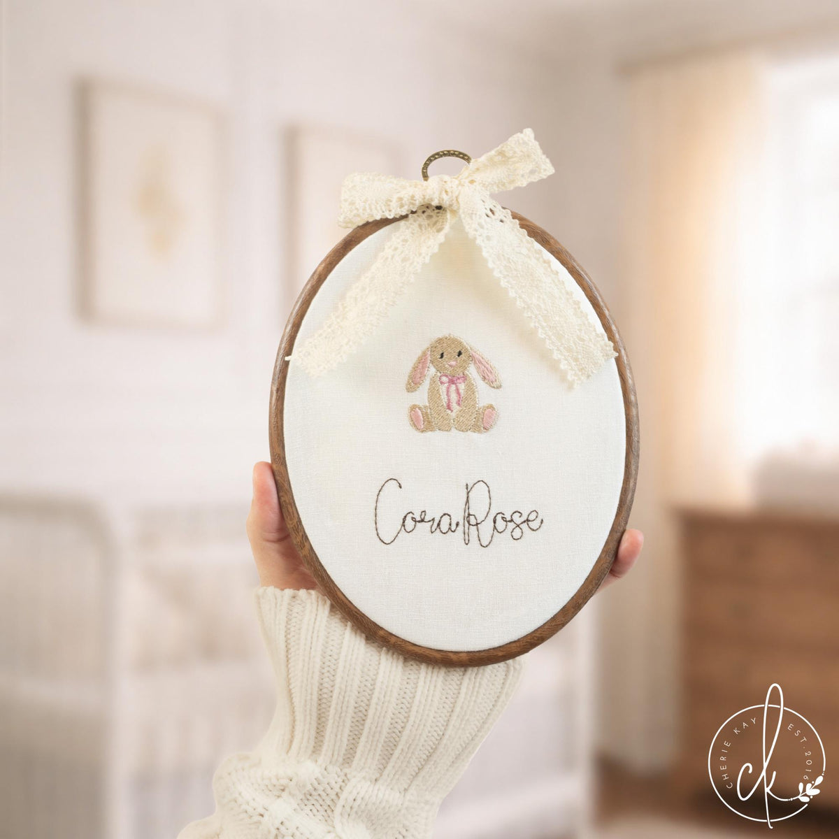 Personalized birth announcement embroidered hoop with baby bunny, pink bow, and custom name in baby girl nursery.