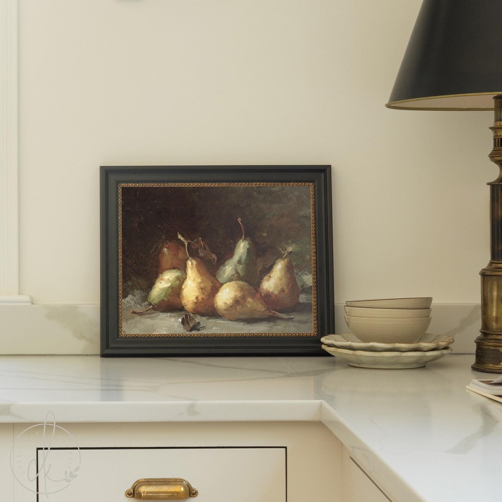 Pear still life framed canvas print in black wood frame with gold beaded trim, displayed on a kitchen counter.