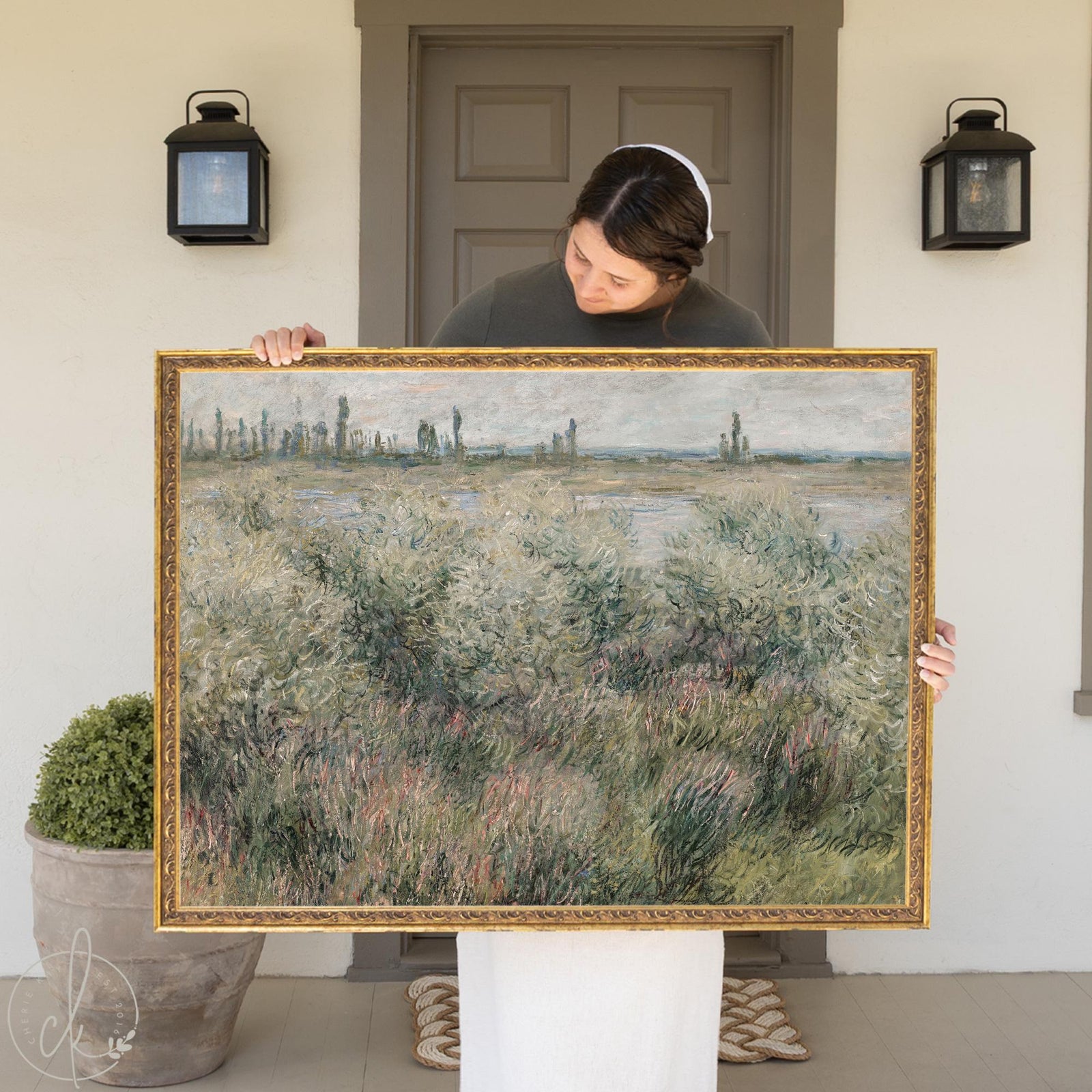 Monet landscape painting of Banks of the Seine near Vétheuil in an ornate gold frame held on a front porch.