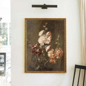 Moody floral wall art of hollyhocks in cream, burgundy, and soft peach in an ornate gold wood frame on a cream wall.