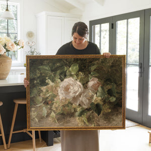 Rose still life canvas print with cream and blush roses on dark green foliage, framed in an ornate gold wood frame.