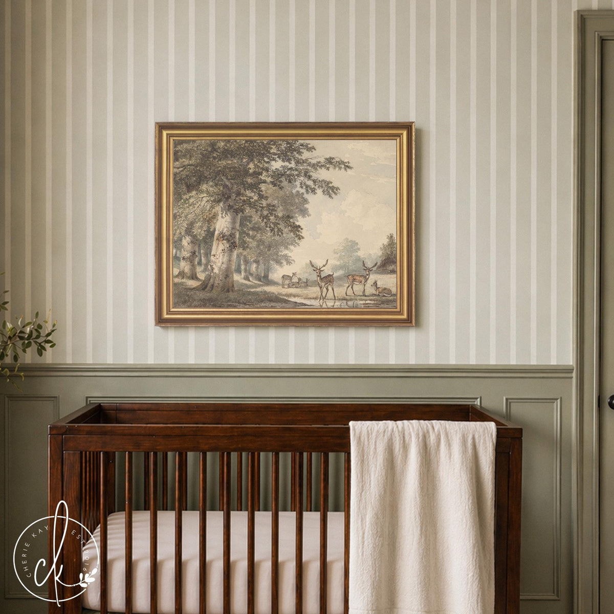 Vintage deer artwork in a gold frame showing stags by a forest stream, hung above a dark wood crib in a sage nursery
