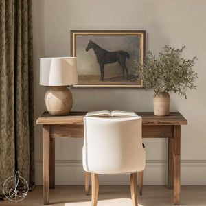 Antique horse print of a dark bay standing in profile, in an ornate gold frame, hanging above a console in a study.