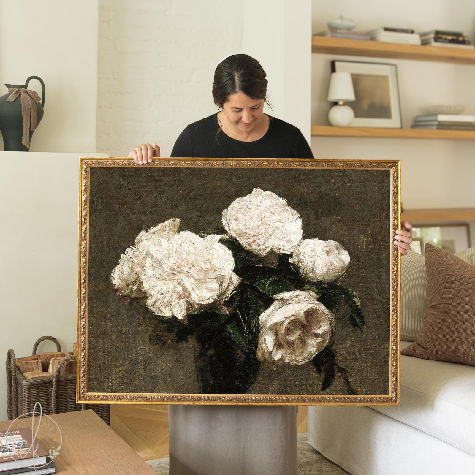 Moody floral wall art with white roses in a gold wood frame, hung above a cream sofa in a living room.