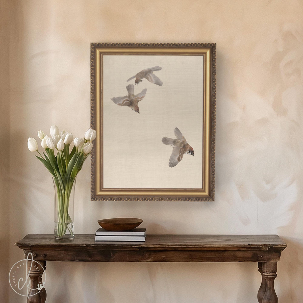 Sparrow art with three birds in flight on canvas in an ornate gold frame, hanging above a console table.