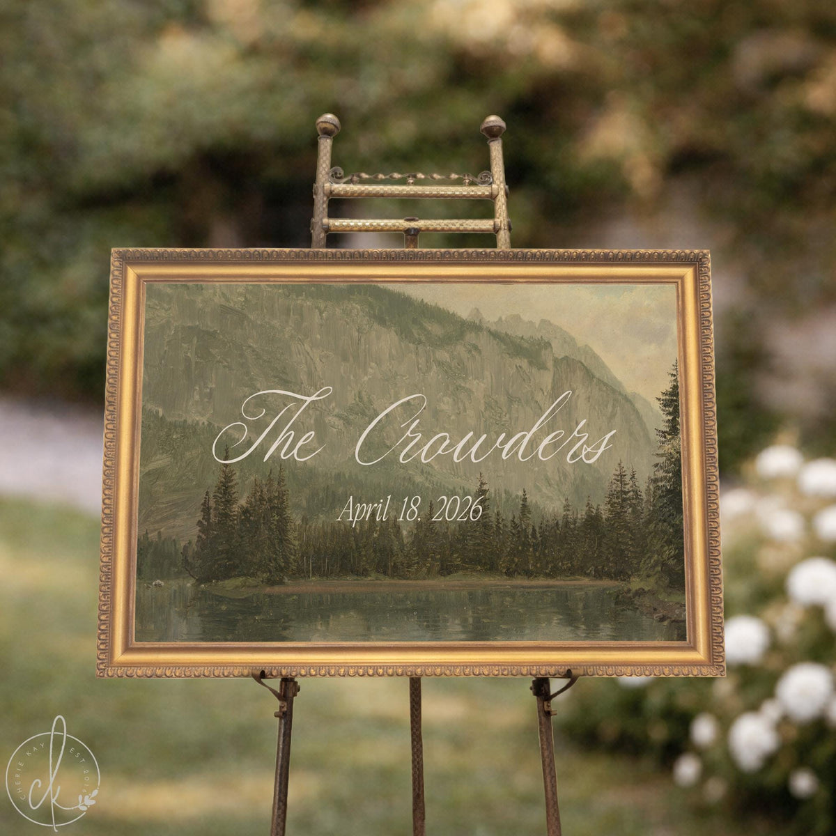 Last name wedding sign with a vintage mountain lake painting in a gold frame on an easel