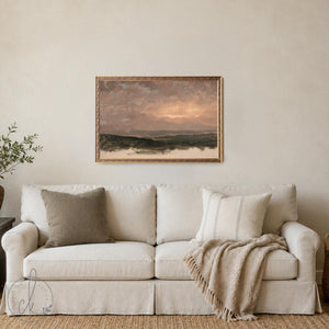 Evening sky painting framed canvas with rose and gold sunset over dark green hills in an ornate gold frame above a beige sofa