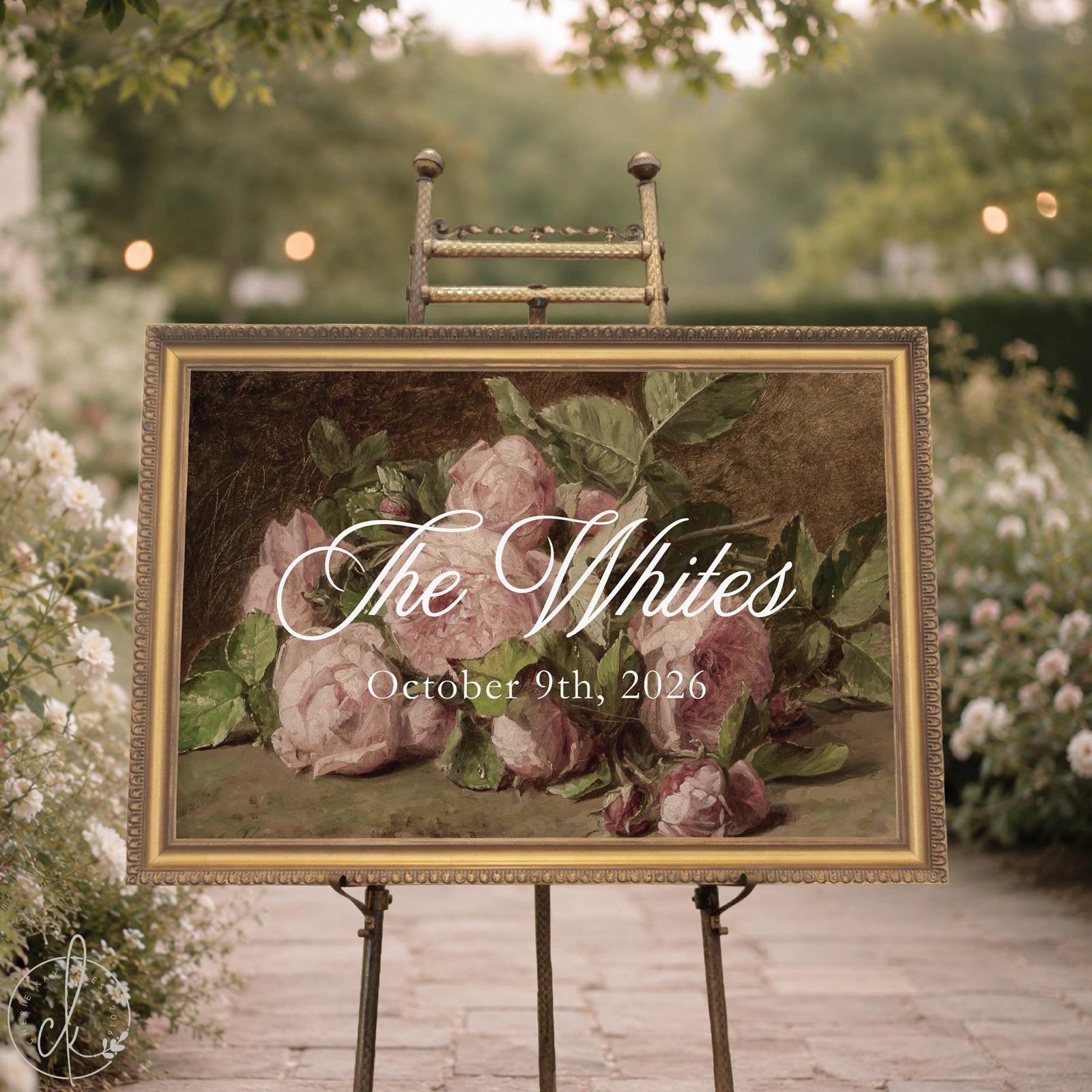 Floral welcome sign with last name and wedding date over a vintage pink rose painting in a gold frame, shown on an easel.
