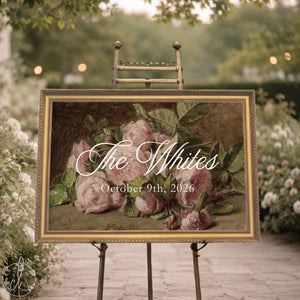 Floral welcome sign with last name and wedding date over a vintage pink rose painting in a gold frame, shown on an easel.