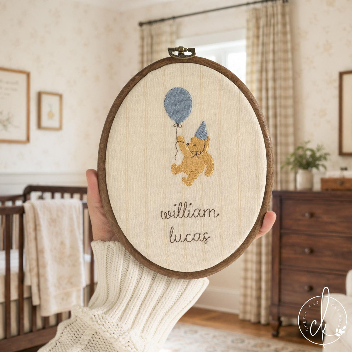 Winnie the Pooh nursery decor hoop with a gold bear holding a blue balloon above a custom name in brown script