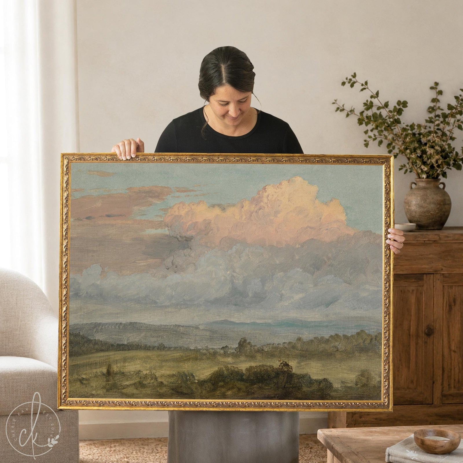 Framed countryside landscape canvas print with pastel clouds over a green valley, shown in an ornate gold frame.