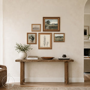 Gallery wall of five vintage landscape prints and white roses in gold frames above a wood console table