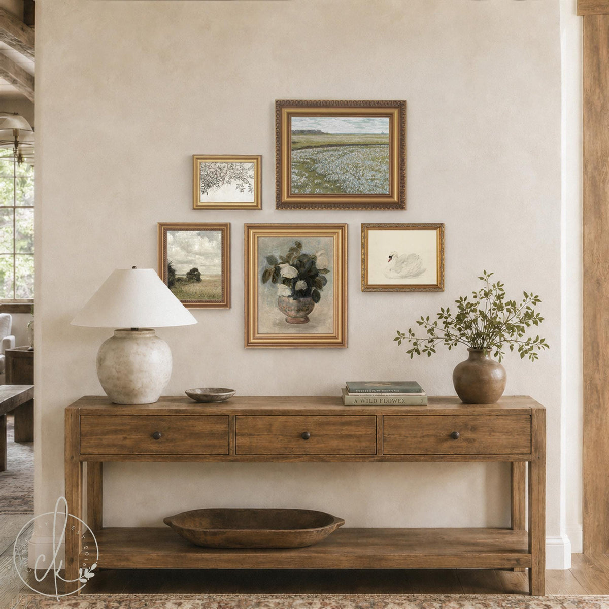 Entryway gallery wall of five gold framed prints with a wildflower field, white swan, and roses above a wood console
