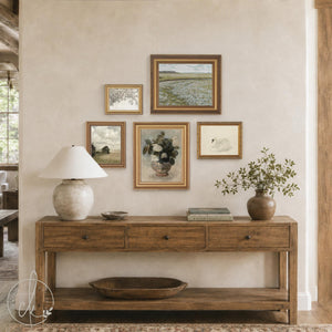 Entryway gallery wall of five gold framed prints with a wildflower field, white swan, and roses above a wood console