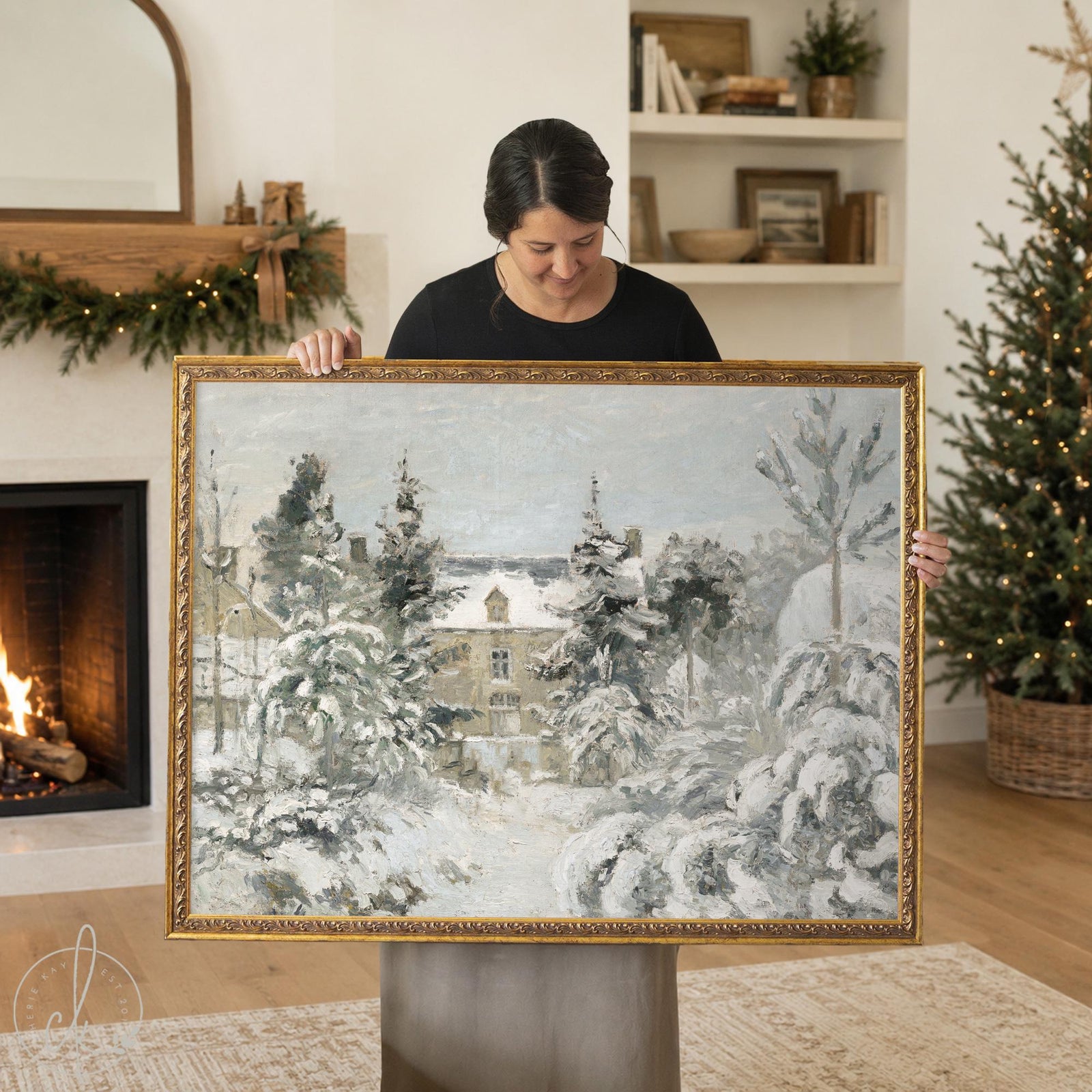 Framed Christmas wall art of a snow covered house behind evergreens, painted look canvas in an ornate gold frame.