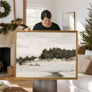 Mantel art of a snowy winter field and evergreen trees in an ornate gold frame, held up in a living room