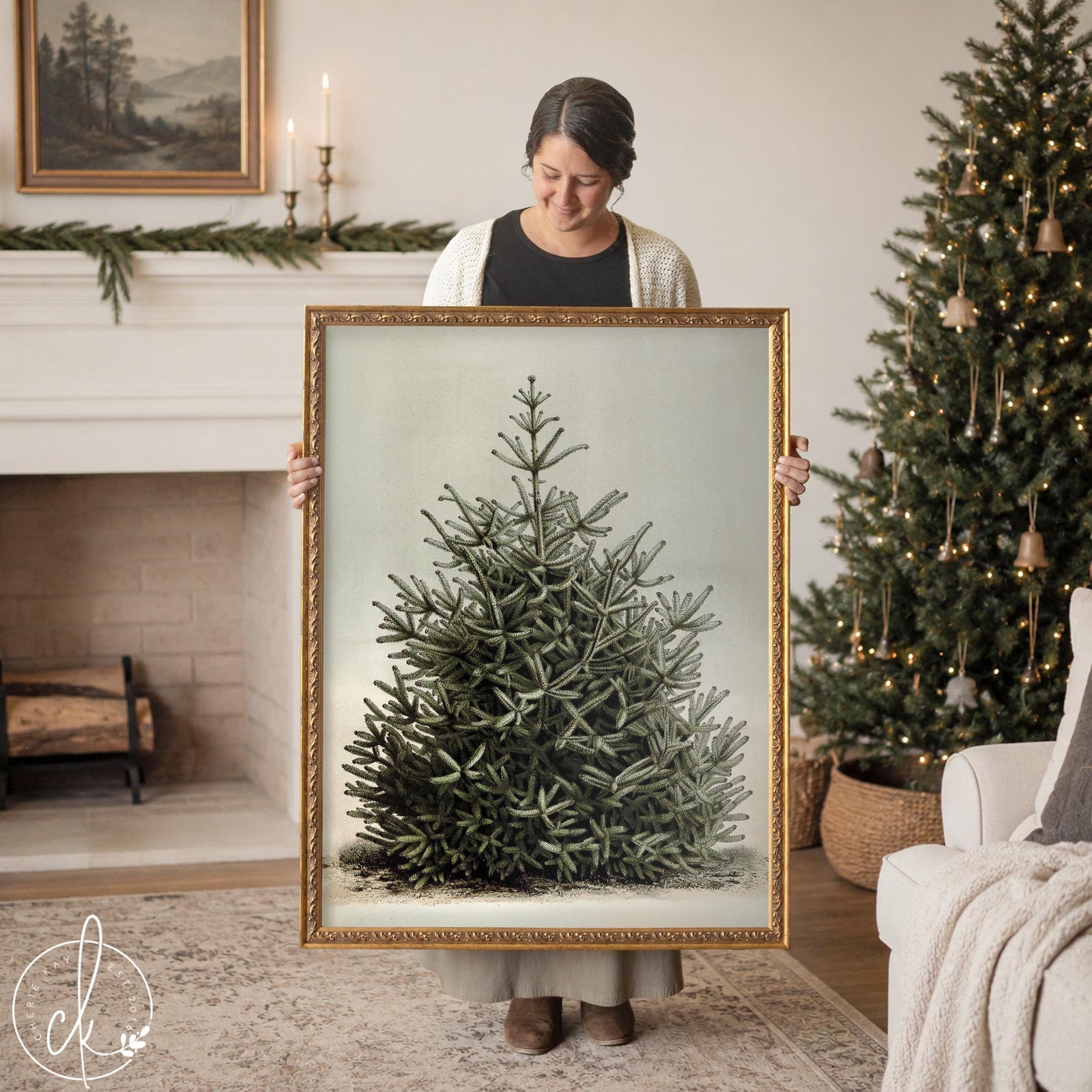 Christmas tree artwork of a snowy evergreen on a pale sage background in a gold frame, held up in a living room