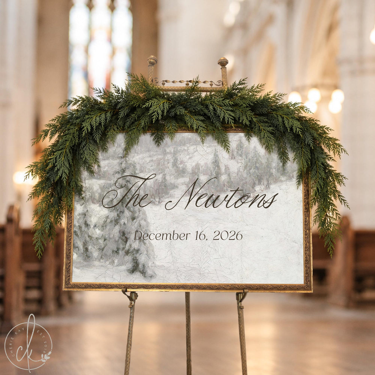 Christmas wedding decor sign with a family name and est. year over a snowy pine hillside in an ornate gold frame