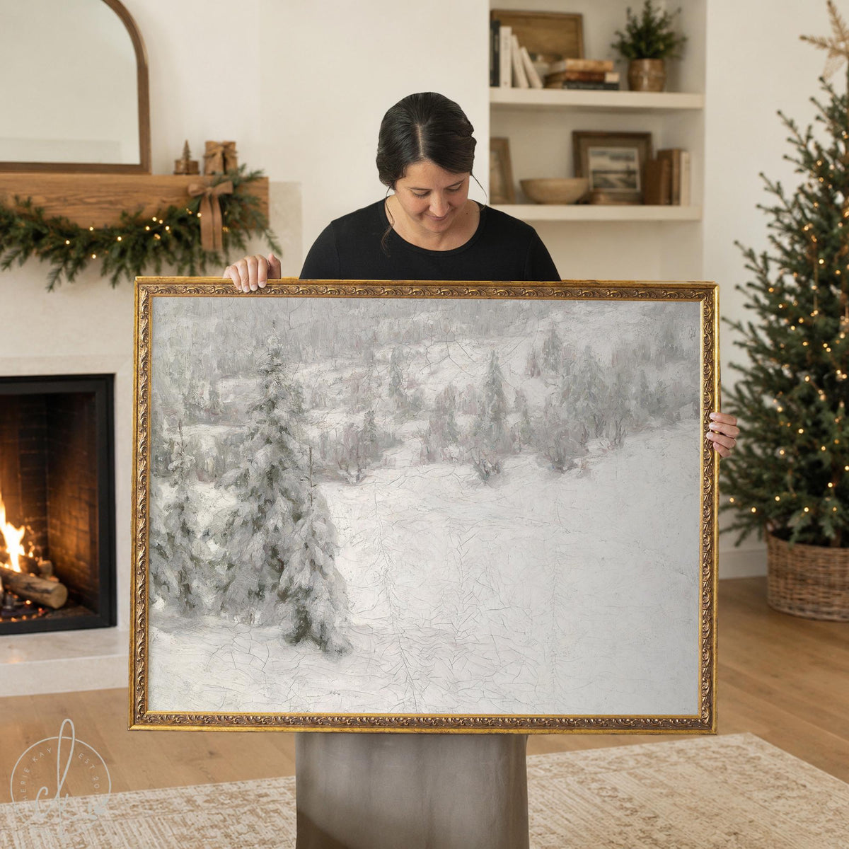 Vintage christmas painting of a snowy pine hillside in an ornate gold frame, held up in a living room