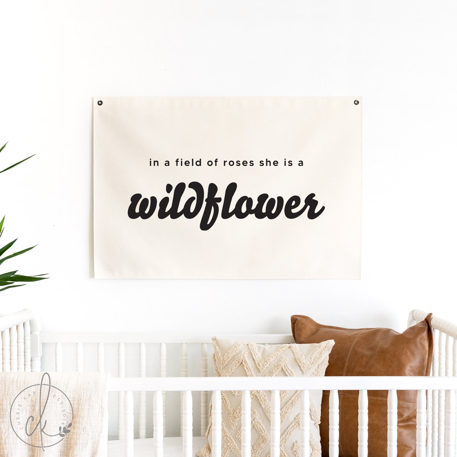 Decorative banner with 'in a field of roses she is a wildflower' text above a crib.