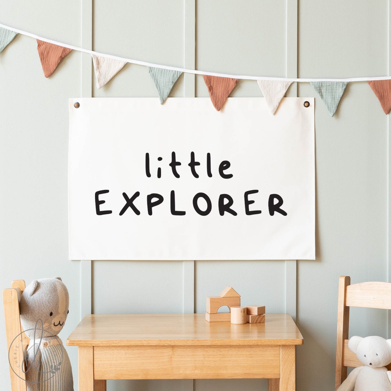 Children's room with a 'little explorer' sign, wooden table, and toys.