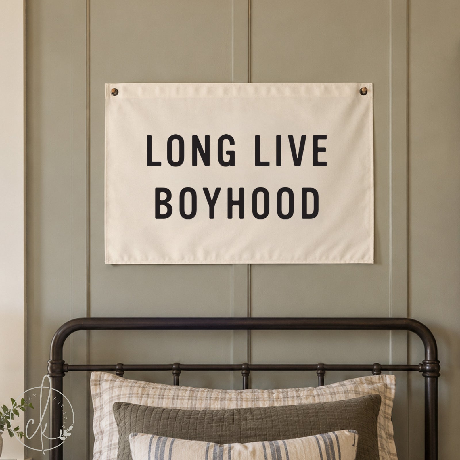 A rectangular white fabric wall banner featuring the black text LONG LIVE BOYHOOD in a bold sans-serif font. The banner is mounted with metal grommets in the top corners, displaying a clean, minimalist design for wall decor.