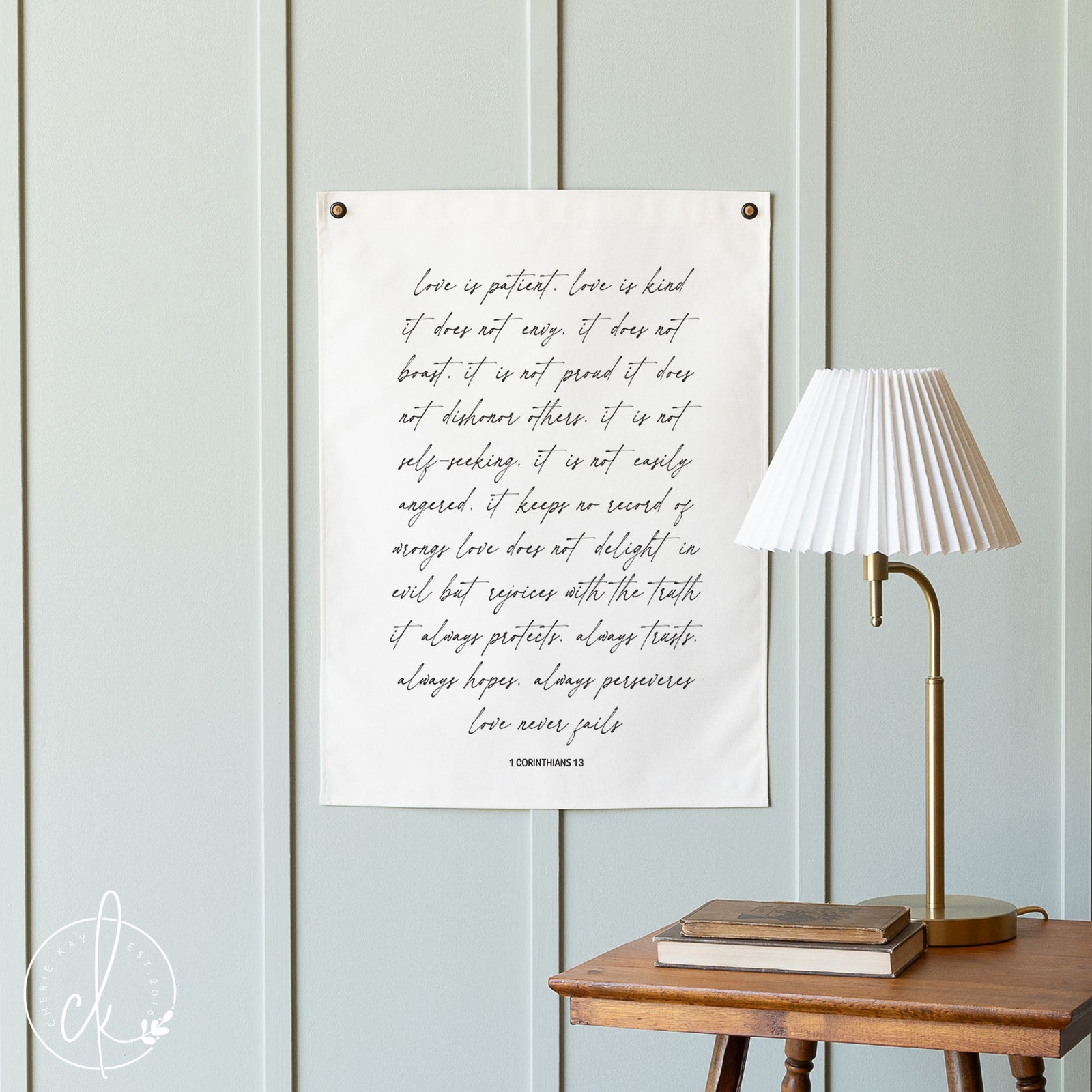 Poster with text on a wall next to a lamp and books on a wooden table.