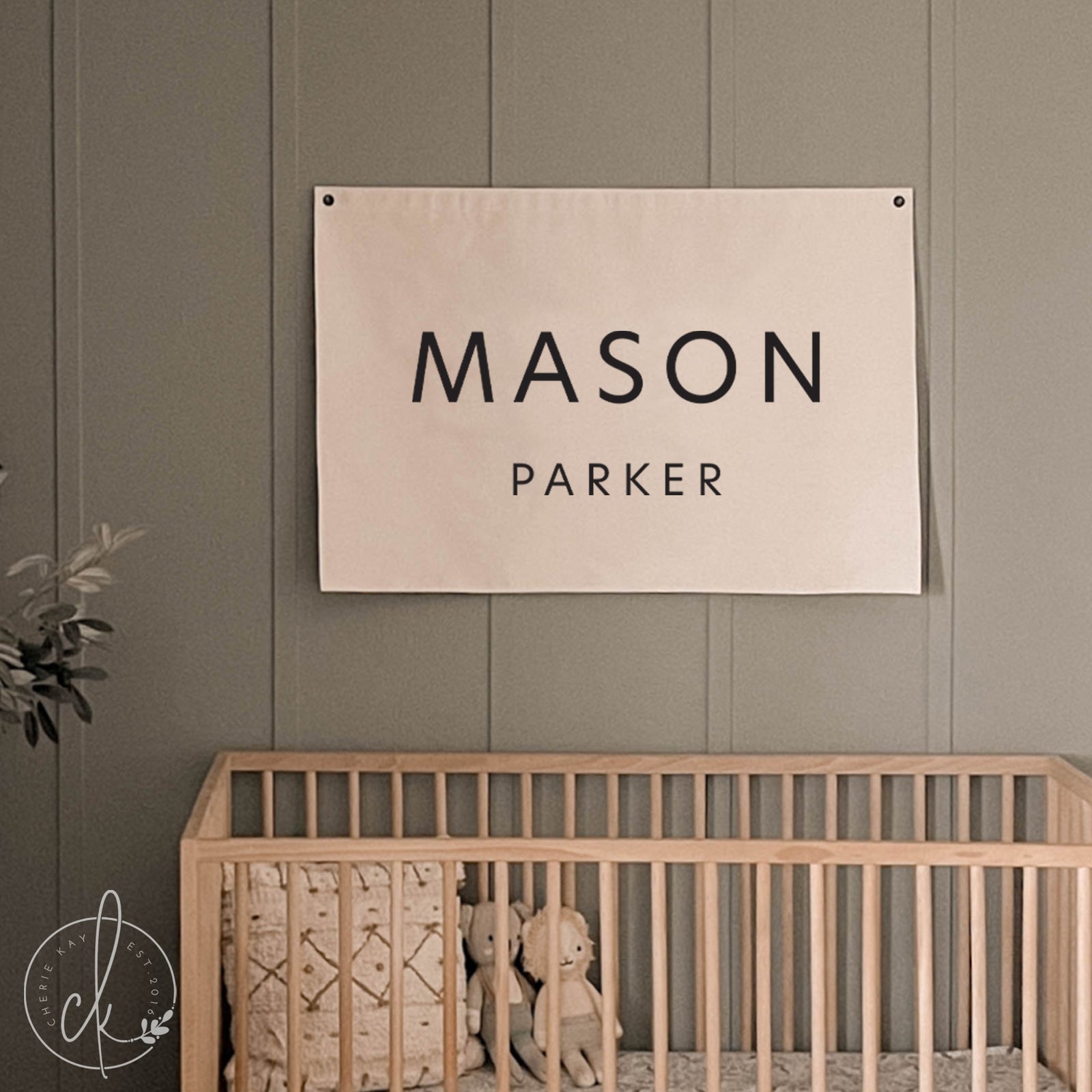Nursery room with a crib and a wall hanging displaying 'MASON PARKER'.