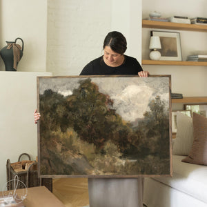Framed moody landscape painting in earth tones with natural wood frame, perfect as neutral wall art for living room or bedroom.