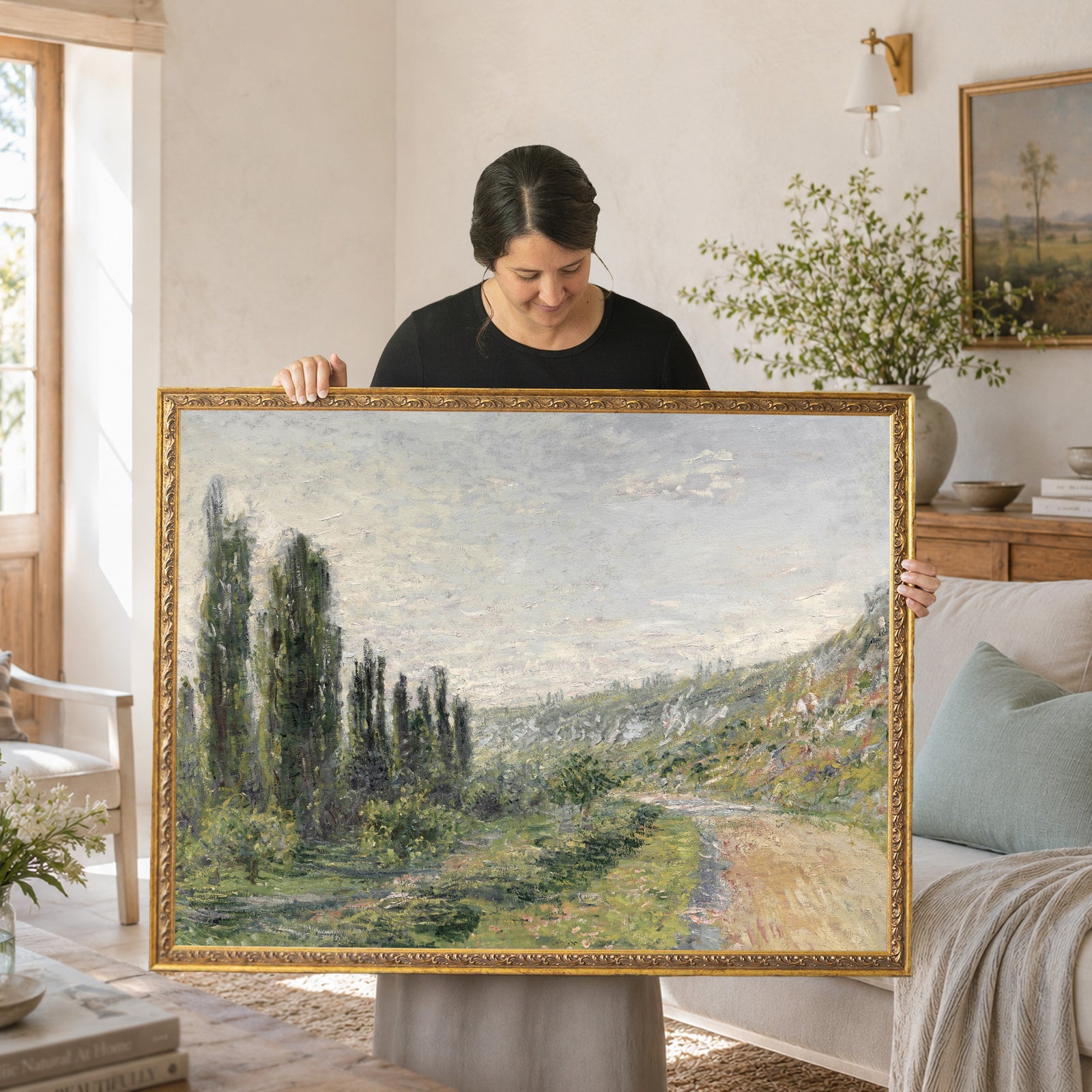 Woman holding French impressionist art framed canvas print of Monet La Route de Vetheuil landscape with poplar trees.