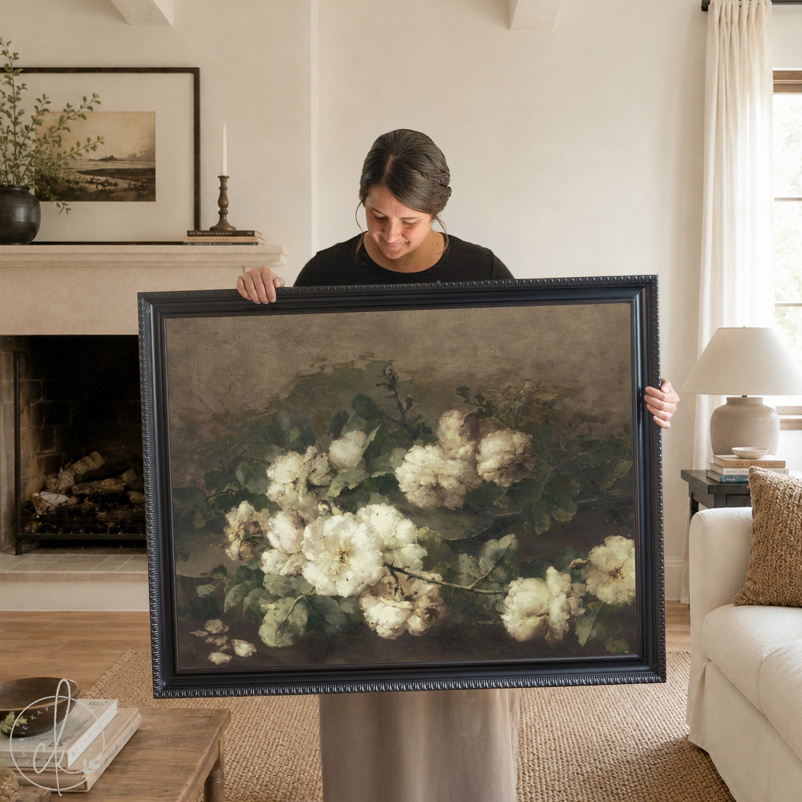 Framed vintage floral painting of white roses with green foliage, hanging above a modern black cabinet in a neutral-toned living room. The artwork features an ornate gold frame and a muted, antique-style background, complementing the minimal, elegant decor.