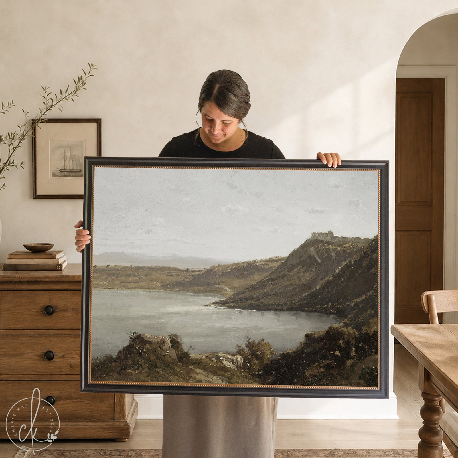 Framed vintage coastal art with gold frame and calm water landscape over cliffs.