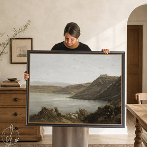 Framed vintage coastal art with gold frame and calm water landscape over cliffs.