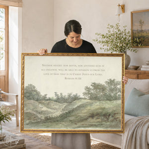 Framed vintage landscape art with Romans 8:39 Bible verse, with woman holding it. framed in vintage ornate gold