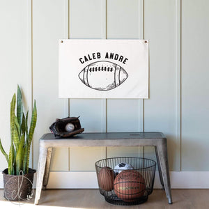 Personalized football canvas banner with custom name hanging in a baby boy’s nursery