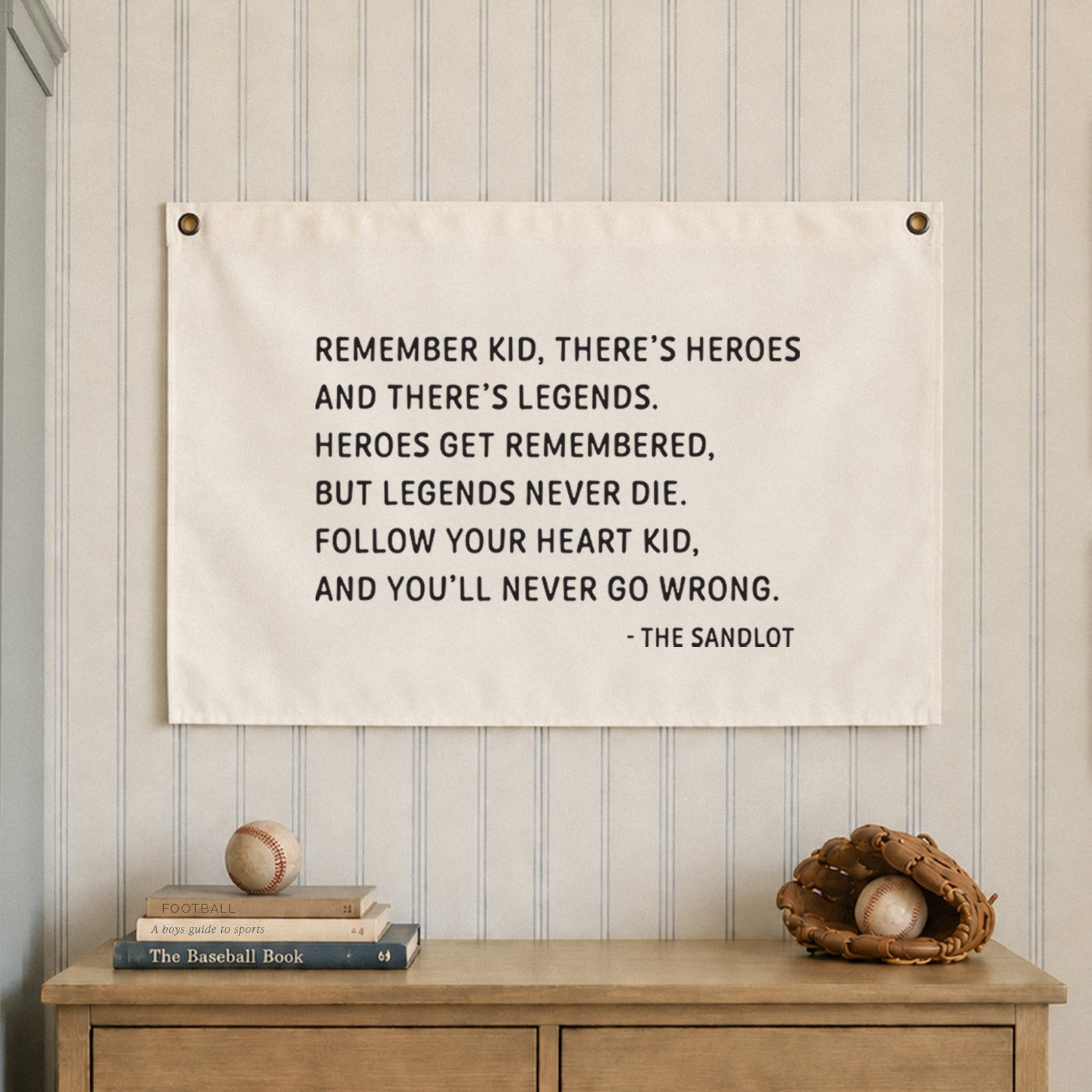 A white rectangular fabric wall hanging featuring black printed text that reads: REMEMBER KID, THERE'S HEROES AND THERE'S LEGENDS. HEROES GET REMEMBERED, BUT LEGENDS NEVER DIE. FOLLOW YOUR HEART KID, AND YOU'LL NEVER GO WRONG. - THE SANDLOT.