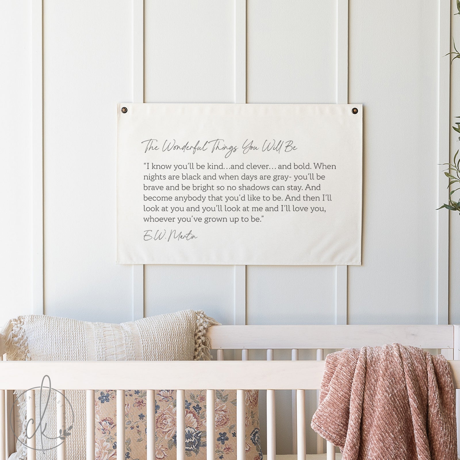 Textual artwork on a wall above a crib with bedding