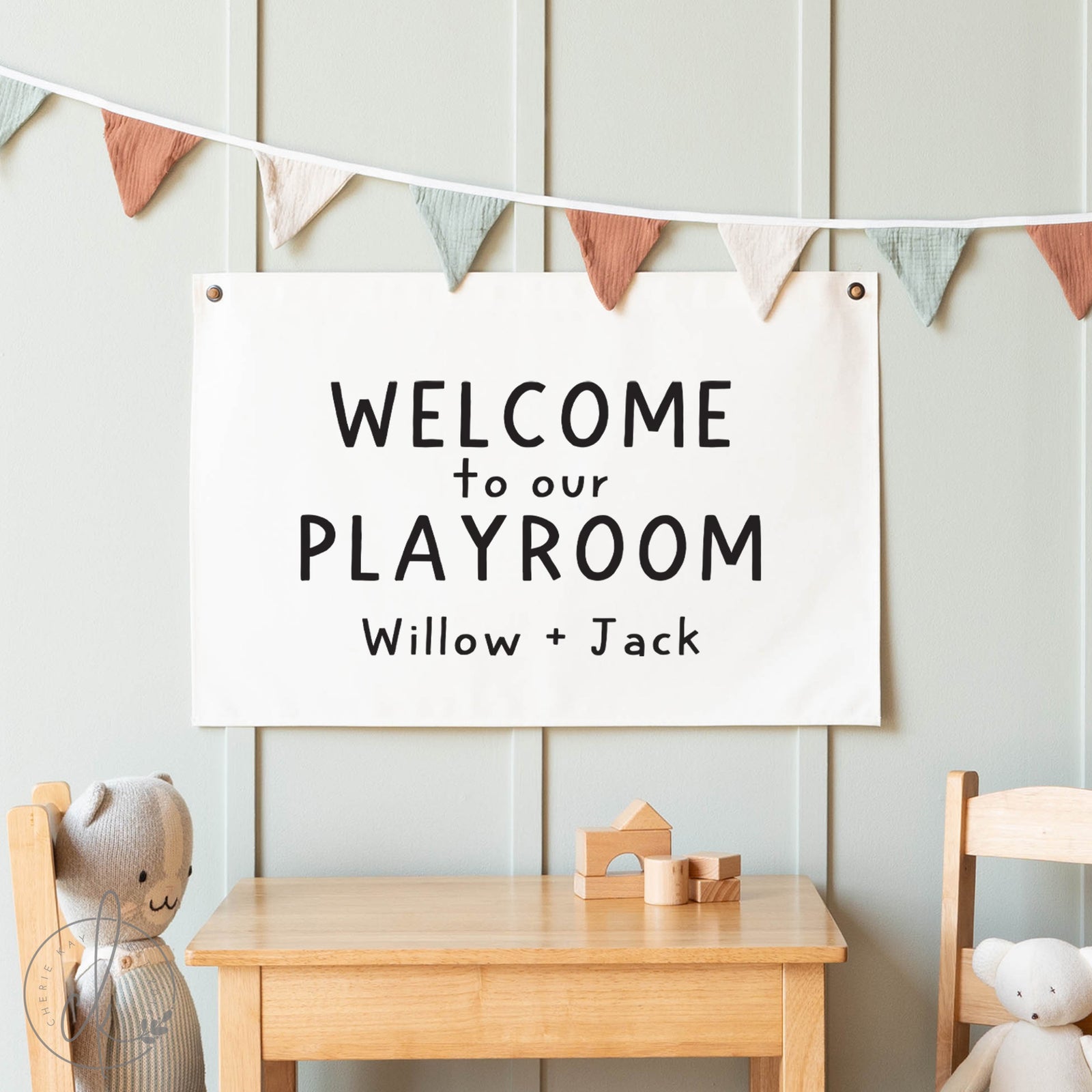 Playroom sign with 'Welcome to our Playroom Willow + Jack' text, wooden table, and chairs with teddy bears.