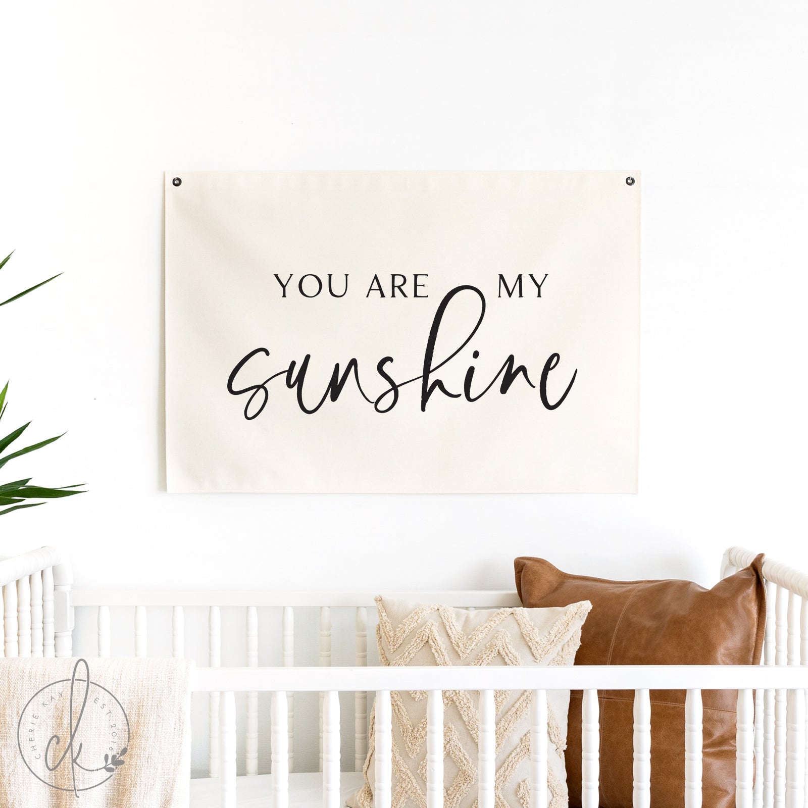 Decorative banner with 'You are my sunshine' text hanging above a crib.